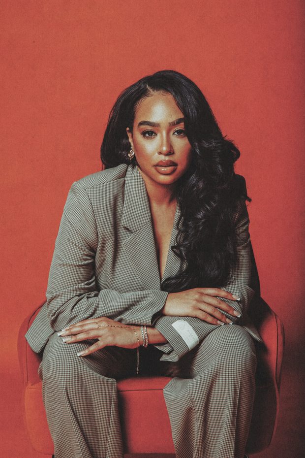 B. Simone seated in a checked suit against a deep red backdrop.